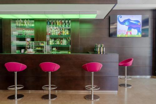 a bar with pink stools in front of a counter at Ariha Hotel Cosenza in Cosenza