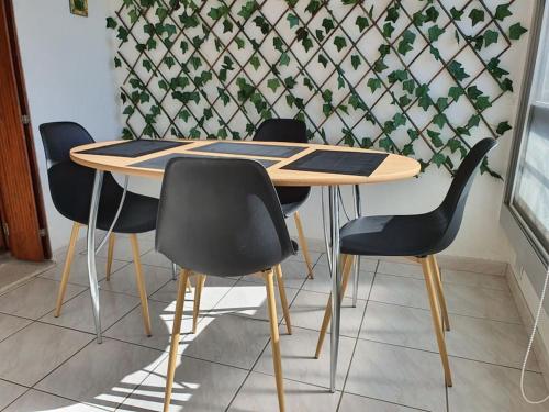 une table en bois avec quatre chaises noires dans la chambre dans l'établissement Caravelle T1 lumineux au calme à 5 mn de la mer, à Argelès-sur-Mer