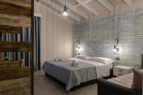 a bedroom with two beds and a brick wall at Corten Hotel in Santa Maria di Licodia
