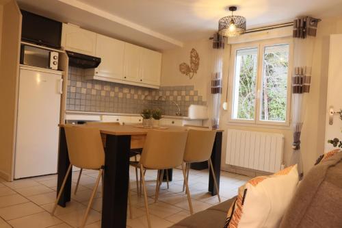 une cuisine avec une table, des chaises et un réfrigérateur dans l'établissement Naou Costes, Modernité et Confort au cœur des montagnes, à Luz-Saint-Sauveur