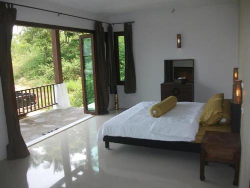 a bedroom with a large bed and a balcony at Sea View Villa in Thong Nai Pan Yai