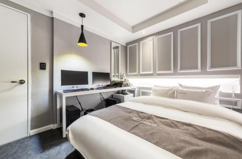 een slaapkamer met een bed en een bureau met 2 monitors bij SL Hotel in Incheon