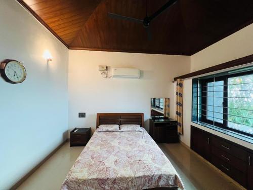 um quarto com uma cama e um relógio na parede em Anant Beach Villa em Ratnagiri