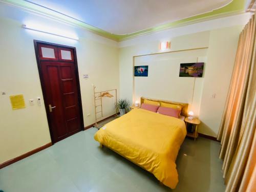 a bedroom with a yellow bed and a red door at Su Homestay in Cao Bằng