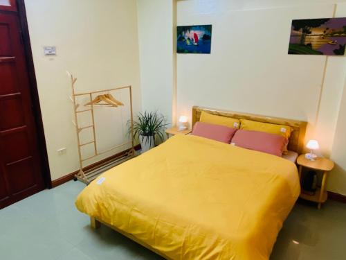 a bedroom with a yellow bed with two pink pillows at Su Homestay in Cao Bằng