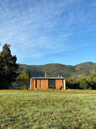 a small wooden building in a field with mountains in the background at Clareira Cabanas in Gonçalves