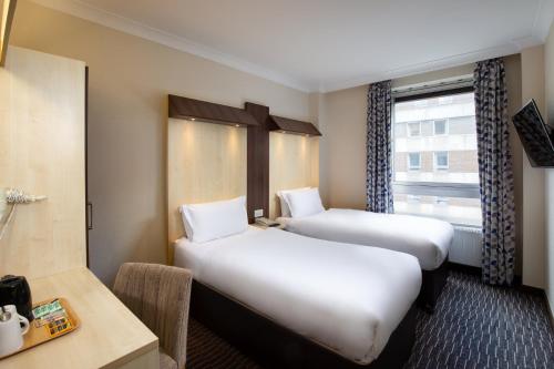 a hotel room with two beds and a window at Royal National Hotel in London