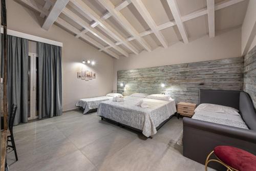 a bedroom with two beds and a stone wall at Corten Hotel in Santa Maria di Licodia