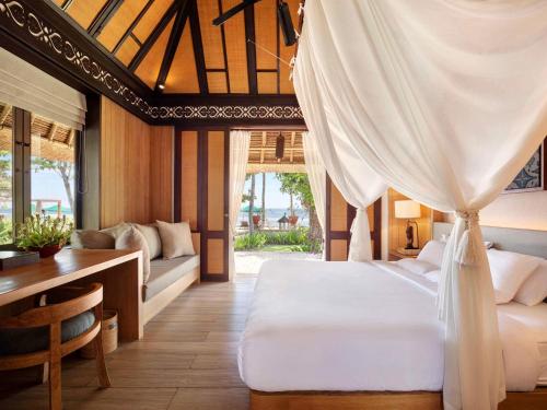 a bedroom with a bed and a desk and a table at Novotel Bali Benoa in Nusa Dua