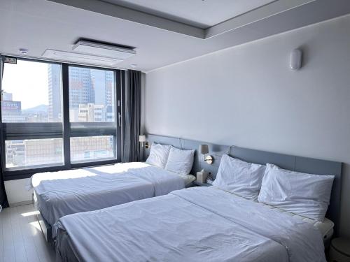 Cette chambre comprend deux lits et une grande fenêtre. dans l'établissement Gurujam, à Daegu
