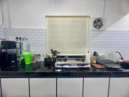 a kitchen counter top with a stove and a window at Homestay Rumah Puteh Melaka in Kampong Bukit Katil