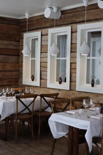 un restaurant avec des tables blanches, des chaises et des fenêtres dans l'établissement Aurora Estate, à Ylläsjärvi
