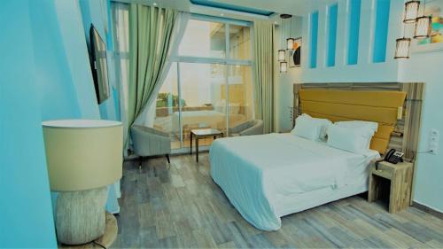 um quarto com uma grande cama branca e uma janela em Hôtel du Phare em Kribi