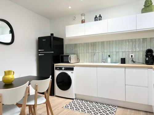 une cuisine avec des armoires blanches et un réfrigérateur noir dans l'établissement Maison rénovée 4 personnes - Prox Lille, à Marquette-lès-Lille