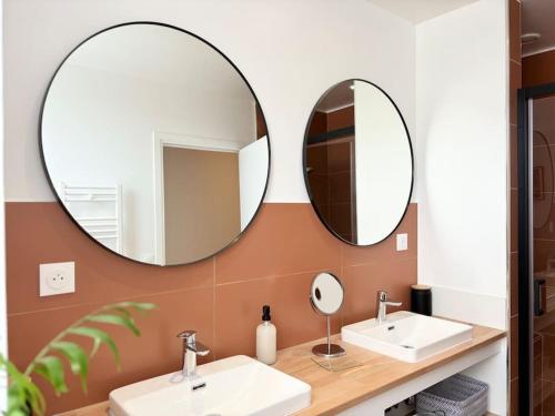 two mirrors on a wall above two sinks in a bathroom at Maison rénovée 4 personnes - Prox Lille in Marquette-lès-Lille