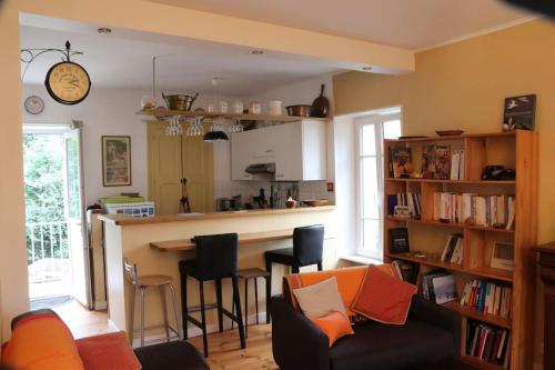 un salon avec un canapé et un bar avec des chaises dans l'établissement Maison Dinannaise -Les Roses-, à Dinan