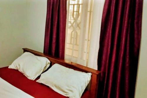 een slaapkamer met rode gordijnen en een bed met 2 kussens bij shiks appartment in Malindi