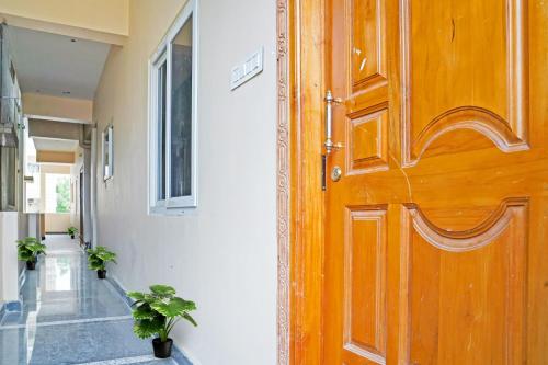 drewniane drzwi w korytarzu z dwoma doniczkami w obiekcie OYO NSK Mahanadu Extension w mieście Gunadala