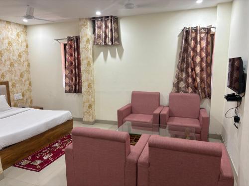 Hotel ARRAJ, Raipur في رايبور: غرفة نوم بسرير وكرسيين وطاولة