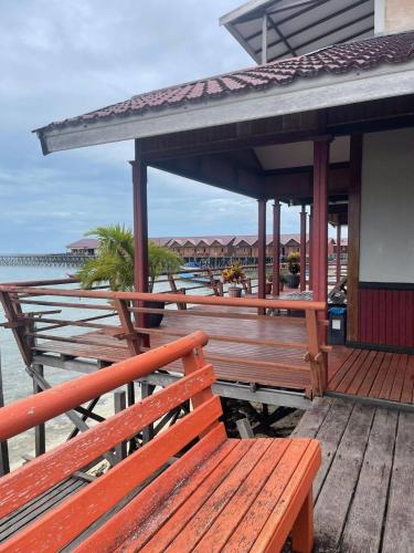 una terraza de madera con bancos en un muelle en Derawan Beach Cafe and Cottage en Derawan Islands