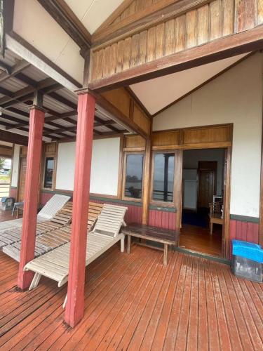 un porche con bancos en una terraza de madera en Derawan Beach Cafe and Cottage en Derawan Islands