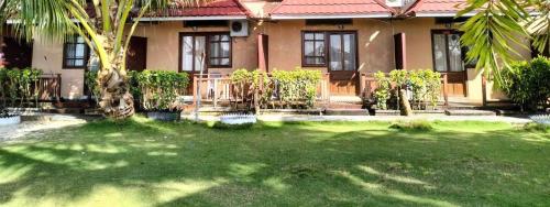 una casa con un patio verde delante de ella en Derawan Beach Cafe and Cottage en Derawan Islands