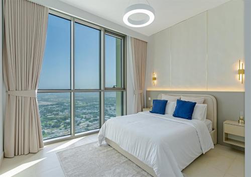 a bedroom with a bed with blue pillows and large windows at Downtown Views 4702 in Dubai