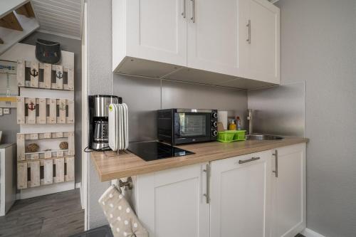 a kitchen with white cabinets and a black microwave at Ferienwohnung 2 Am Rodelberg in Priborn