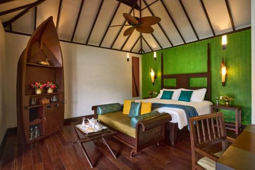 a bedroom with a bed and a couch and a table at Taj Kumarakom Resort and Spa Kerala in Kumarakom