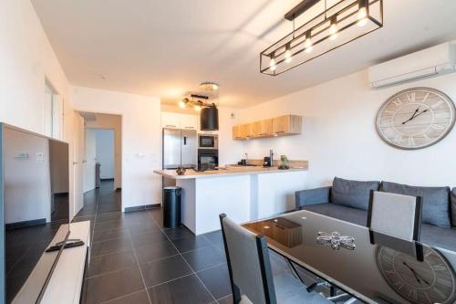 - un salon et une cuisine avec une horloge murale dans l'établissement Location T3 traversant lumineux, à Marseille