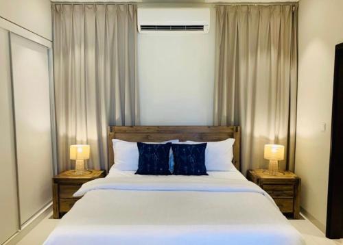 a bedroom with a large white bed with two lamps at Lake View Luxury Suite, Hawana Resort in Salalah