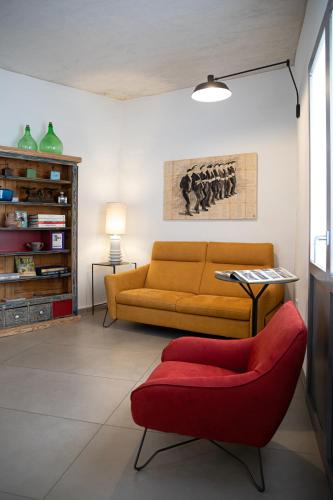 a living room with a couch and a red chair at Domu Qirat - Authentic Rooms & Terraces in Tortolì