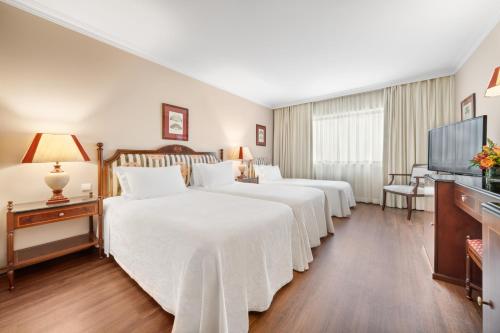 um quarto de hotel com duas camas e uma televisão de ecrã plano em Dom Pedro Lisboa em Lisboa