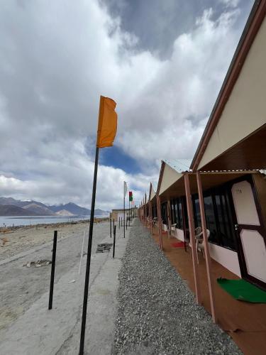 a beach with a row of houses and a yellow flag at Padma Cottage Pangong in Spangmik