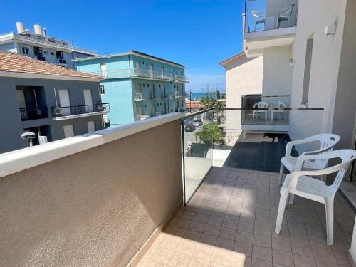 a balcony with two white chairs on a balcony at Hotel Harmony in Rimini
