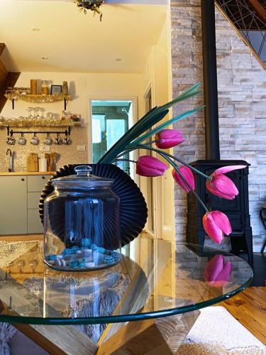 a glass table with a vase with pink flowers on it at WoodMood in Žabljak