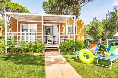 a tiny house with a patio and two chairs at Camping Village Baia Azzurra in Castiglione della Pescaia