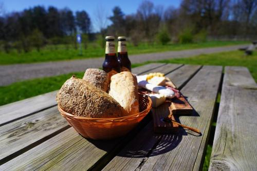 a basket of bread and bottles of beer on a picnic table at Glamperen met eigen badkamer in De Peel voor 6 Pers Happy in Behelp