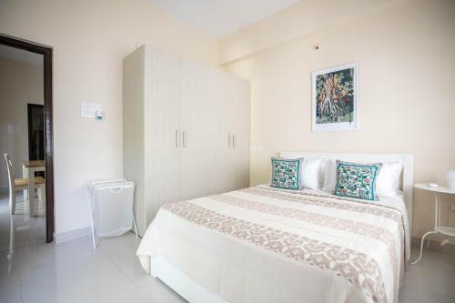 a white bedroom with a large white bed with blue pillows at MyHaus Apartments in Hyderabad