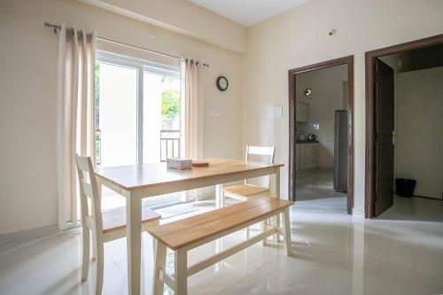 a dining room table with a bench and a window at MyHaus Apartments in Hyderabad