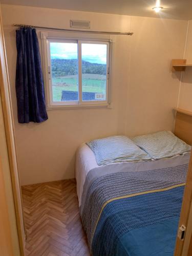 deux lits dans une petite pièce avec une fenêtre dans l'établissement Mobile home 4 saisons au Ranch du Bonheur, à Tourtouse