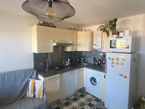 La cuisine est équipée d'un réfrigérateur blanc et d'un four micro-ondes. dans l'établissement Appartement proche des plages, au Cap d'Agde