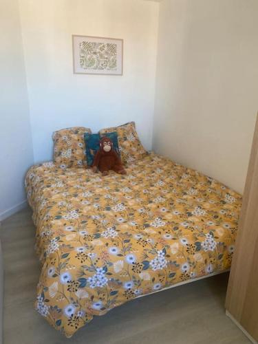 un ours en peluche assis sur un lit dans l'établissement Appartement proche des plages, au Cap d'Agde
