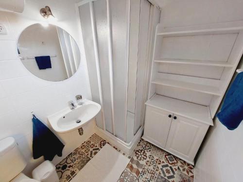 a white bathroom with a sink and a mirror at Mandulás nyaraló in Zánka
