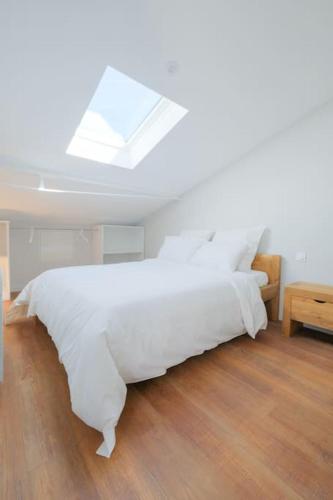 une chambre avec un lit blanc et une lucarne dans l'établissement La Suite Sablaise, à Les Sables-dʼOlonne
