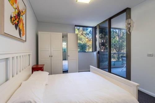 a bedroom with a large white bed and large windows at Walking to GS Station 1 Free Parking Shopping Centre in Sydney
