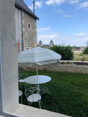 a table and chairs with an umbrella in a yard at Grand gite en rez-de-jardin in Saint-Aignan