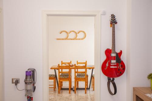 a red guitar hanging on a wall next to a dining room at SeaBreeze Gallipoli - Lido San Giovanni in Gallipoli
