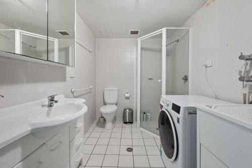 y baño blanco con lavadora. en Spacious Ensuite Room in a City Centre Duplex Apartment-2 en Canberra
