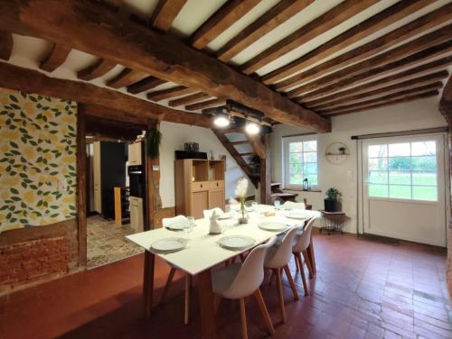 une grande salle à manger avec une table et des chaises blanches dans l'établissement La chaumière de jacquotte linge de lits en option, à Limpiville